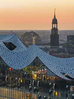 Aerial view of the Elbphilharmonie at sunset with illuminated windows and view over Hamburg
