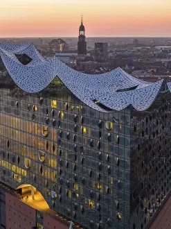 Aerial view of the Elbphilharmonie at sunset with illuminated windows and view over Hamburg