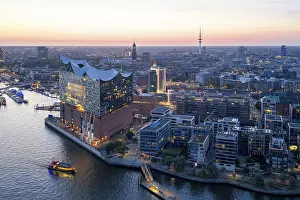 Aerial view of the Elbphilharmonie at sunset with illuminated windows and view over Hamburg