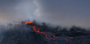 Aerial view, erupting volcano with lava fountains and lava field