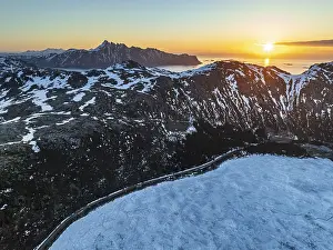 Aerial view of icy lake in front of steep mountains