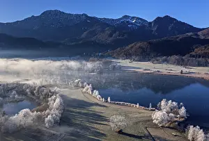 Aerial view of a lake in front of mountains in winter