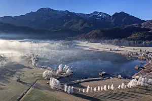 Aerial view of a lake in front of mountains in winter