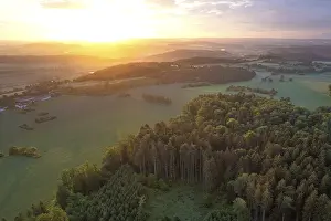 Aerial view of a landscape with forest in the foreground at sunset