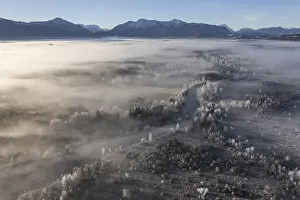 Aerial view of a moor landscape with river in front of mountains in winter