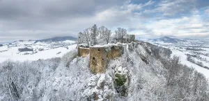 Aerial view, panorama of the snow-covered Hegau volcano Maegdeberg with remains of a castle wall on a cold winter