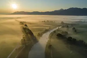 Aerial view of a river in front of mountains in the morning light