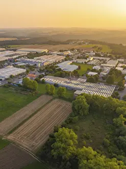 Aerial view of a rural industrial plant with fields and trees at sunset