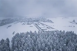 Aerial view of a snowy village surrounded by forests