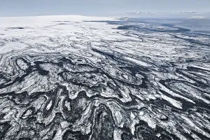 Aerial view, structures of volcanic ash and black lava in the ice and snow of the Vatnajoekull glacier