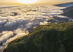 Aerial view of sunrise above clouds and green hills at Fanal mountain