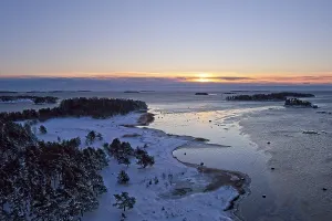 Aerial view of sunrise at seashore on a cold winter day with ice on the shoreline