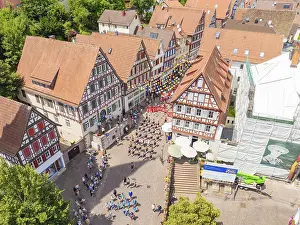Aerial view of a town square surrounded by half-timbered houses with many people at a celebration