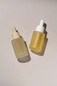 Aesthetic presentation of two skincare serum bottles with droppers casting subtle shadows on a neutral background Ideal