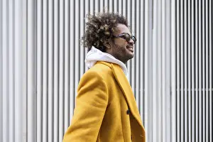 Afro man wearing a stylish mustard coat gazes confidently to the side