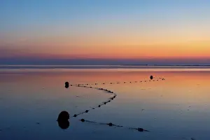 The afterglow and sunset glow of the setting sun in the sky over the calm North Sea on the beach at Utersum