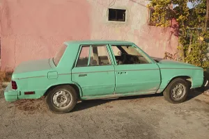 Aged old vintage green car in pink wall Cancun Mexico
