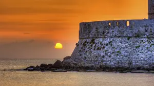 Agios Nikolaos fortress, sunrise behind an old castle wall with gentle sea waves