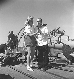 Ake Soederblom, 1910-1965, Swedish actor here during the filming of a feature film on a Swedish warship. He is dressed in a sailor's uniform and is seen dancing with a young blonde woman on the ship's deck during a break in filming
