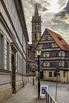 Framed Print : Alley with a view of a half-timbered house and a church tower