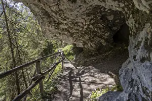 Alpine hiking trail on the rock with grotto cave