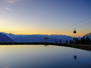 Alpine panorama, gondola of the Jennerbahn cable car reflected in the evening light in an artificial mountain lake