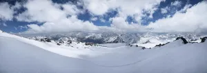 Alpine panorama of the large Caucasian ridge covered with snow on a sunny day with variable clouds