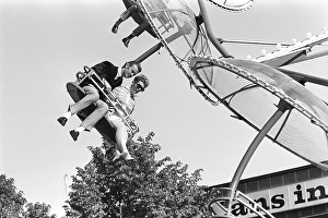 Amusement park in the 1960s. A couple is seen in one of the attractions that are offered on the grounds. They sit next to each other in a seat that moves round and round. Sweden 1968