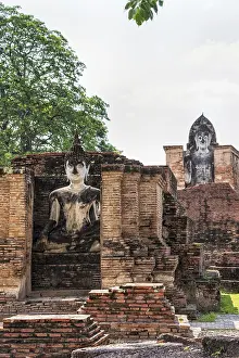 Ancient Buddha statue among the ruins under the bright sun of Wat Maha That temple in Sukhothai Historical Park is an