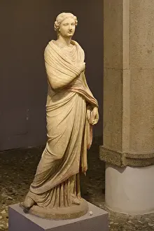 Ancient marble sculpture of a classical woman in a draped robe in the museum