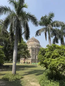 Ancient mausoleum surrounded by palms and trees under a clear sky