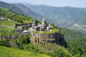 An ancient monastery sits majestically on a hill overlooking a mountainous landscape