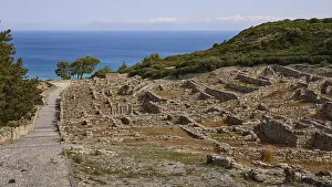 Ancient ruins on a hill with a view of the sea and a path in the foreground