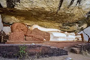 Ancient sandstone sculpture of a Buddha reclining under a rocky outcrop