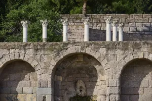 Ancient stone structure with columns and overgrown trees in the background