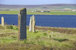 Ancient stones at the edge of a blue lake with green hills in the background
