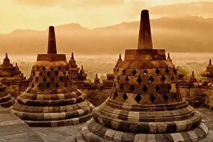 Ancient stupas in Borobudur temple during a warm sunrise