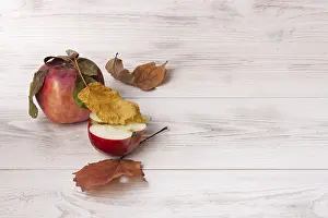Apples and autumn leaves on white wooden background