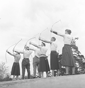 Archery in the 1950s. A group of men and women are standing with their bows and arrows