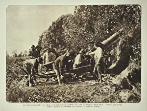 Artillery soldiers firing battery cannon from behind camouflage screen towards battlefield in Flanders during the WWI