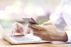Asian Indian businessman using smartphone and laptop computer at outdoor cafeteria