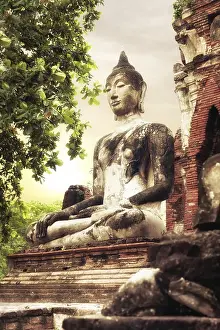 Asian religious architecture. Ancient sandstone sculpture of Buddha at Wat Mahathat ruins under sunset sky