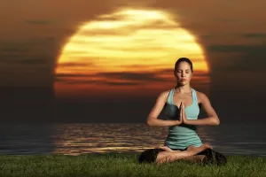 An athletic, beautiful woman practising yoga on the beach at dawn