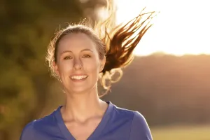 Attractive active young woman out exercising in glowing morning light on a country path through woodland