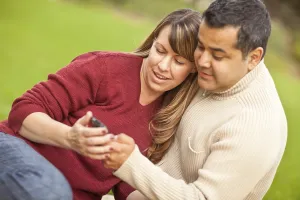 Attractive mixed-race couple enjoying their camera phone in the park