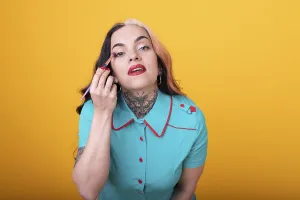 Attractive Woman Applying eye shadow over yellow Studio Background