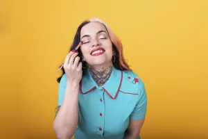 Attractive Woman Applying eye shadow over yellow Studio Background