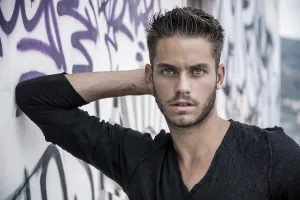 Attractive young man standing against colorful graffiti wall