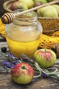 Autumn harvest of apples in the background of the glass jar with fragrant honey