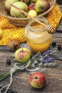 Autumn harvest of apples in the background of the glass jar with fragrant honey